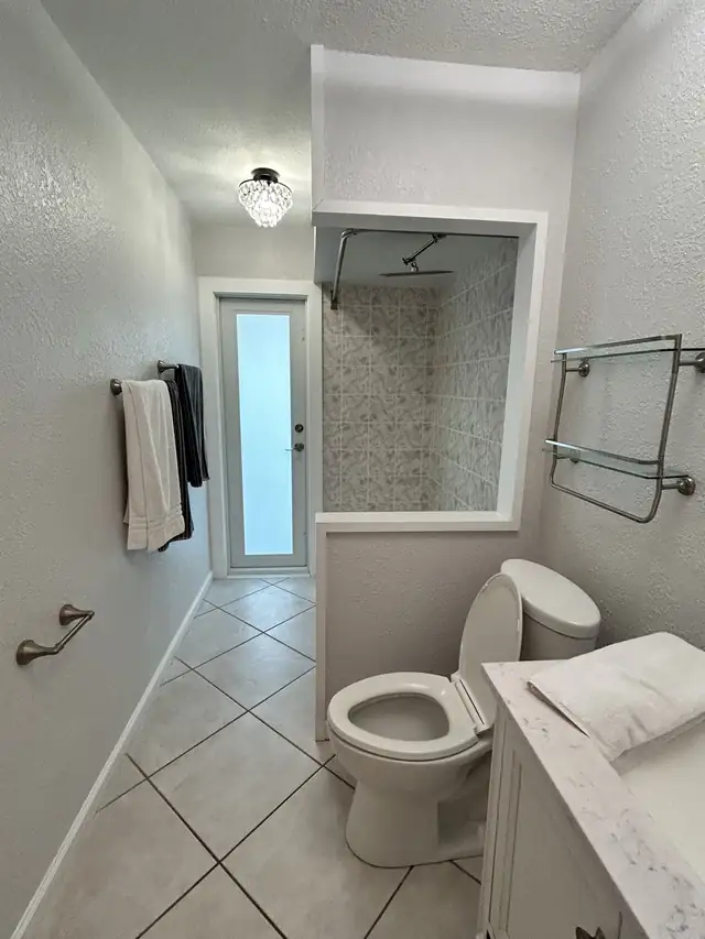 Guest bathroom before remodel with textured walls, old patterned shower tile and diagonal floor tile
